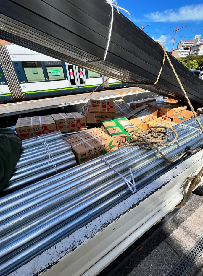秋本産業の配送車。長尺の鋼材と木材を荷台へ積んでいる