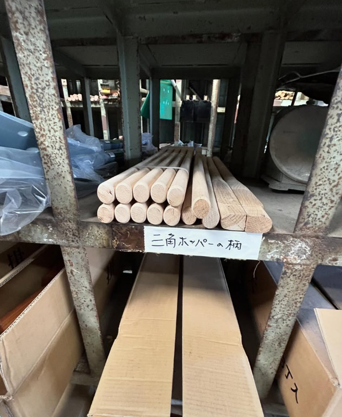 秋本産業の資材保管棚。木製の柄材を種類ごとにラックへ収めている