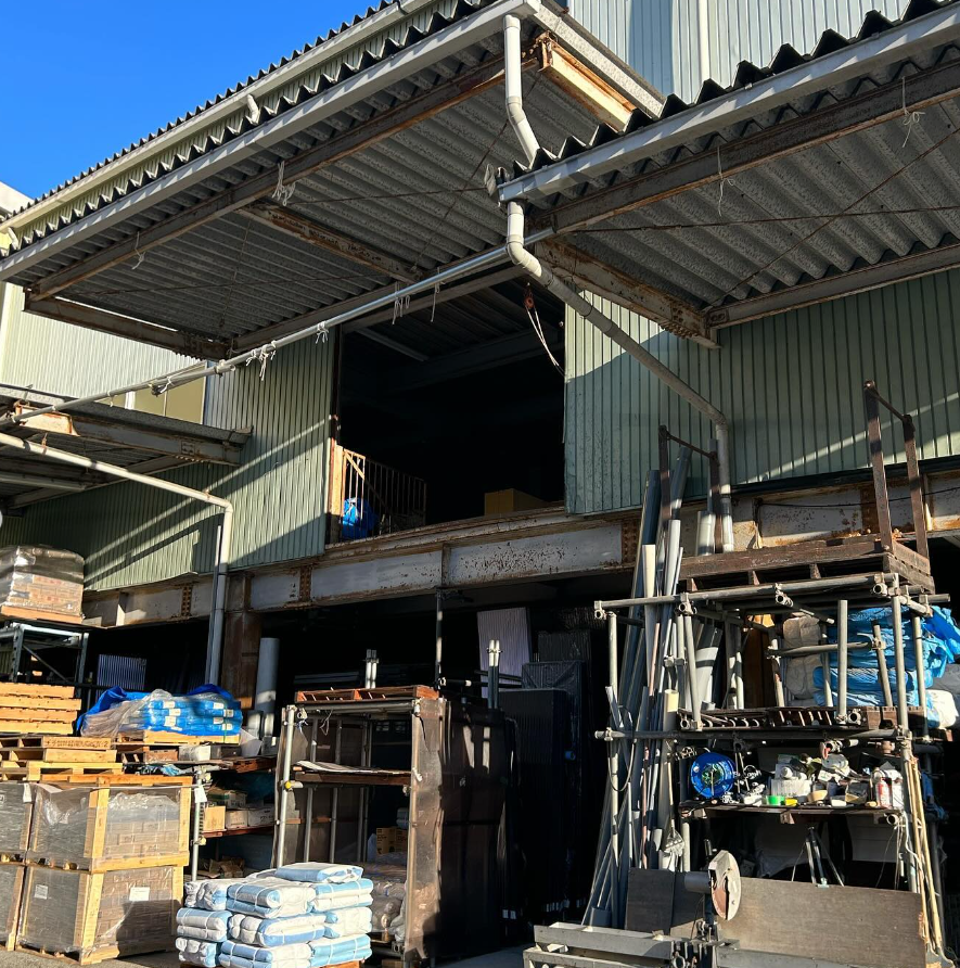秋本産業の倉庫外観。折板屋根の建屋に資材を保管している